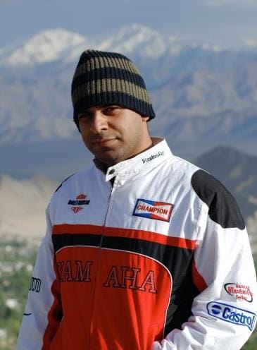 Akram Khan in motorsport racing gear in the mountains